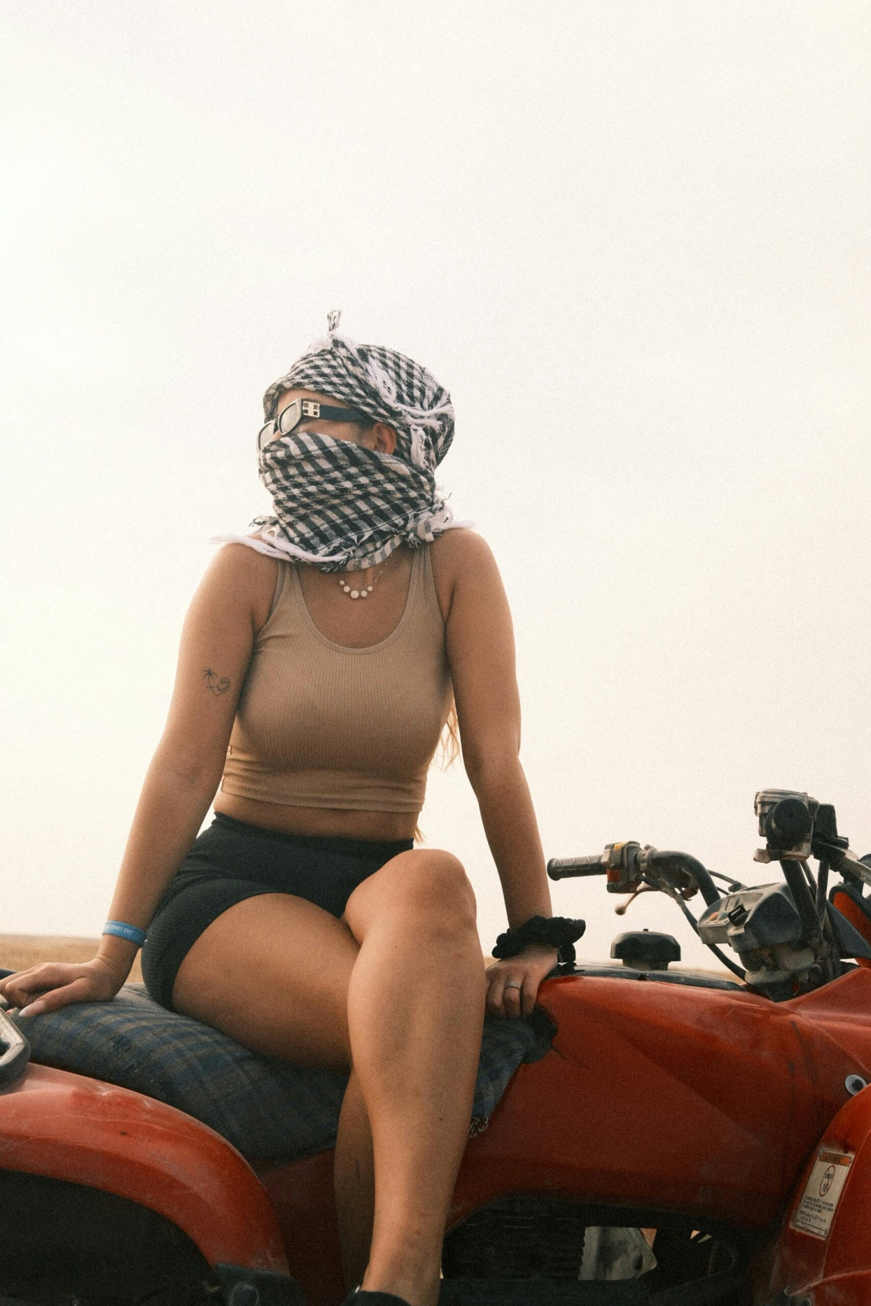 Woman with headscarf sitting on ATV, ready for adventure in the desert.